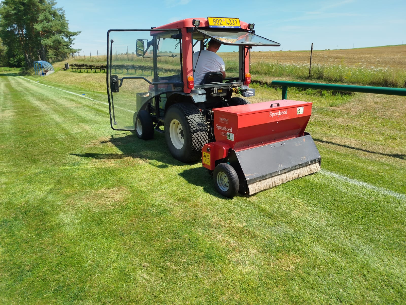 Traktor se specializovaným strojem při regeneraci fotbalového hřiště