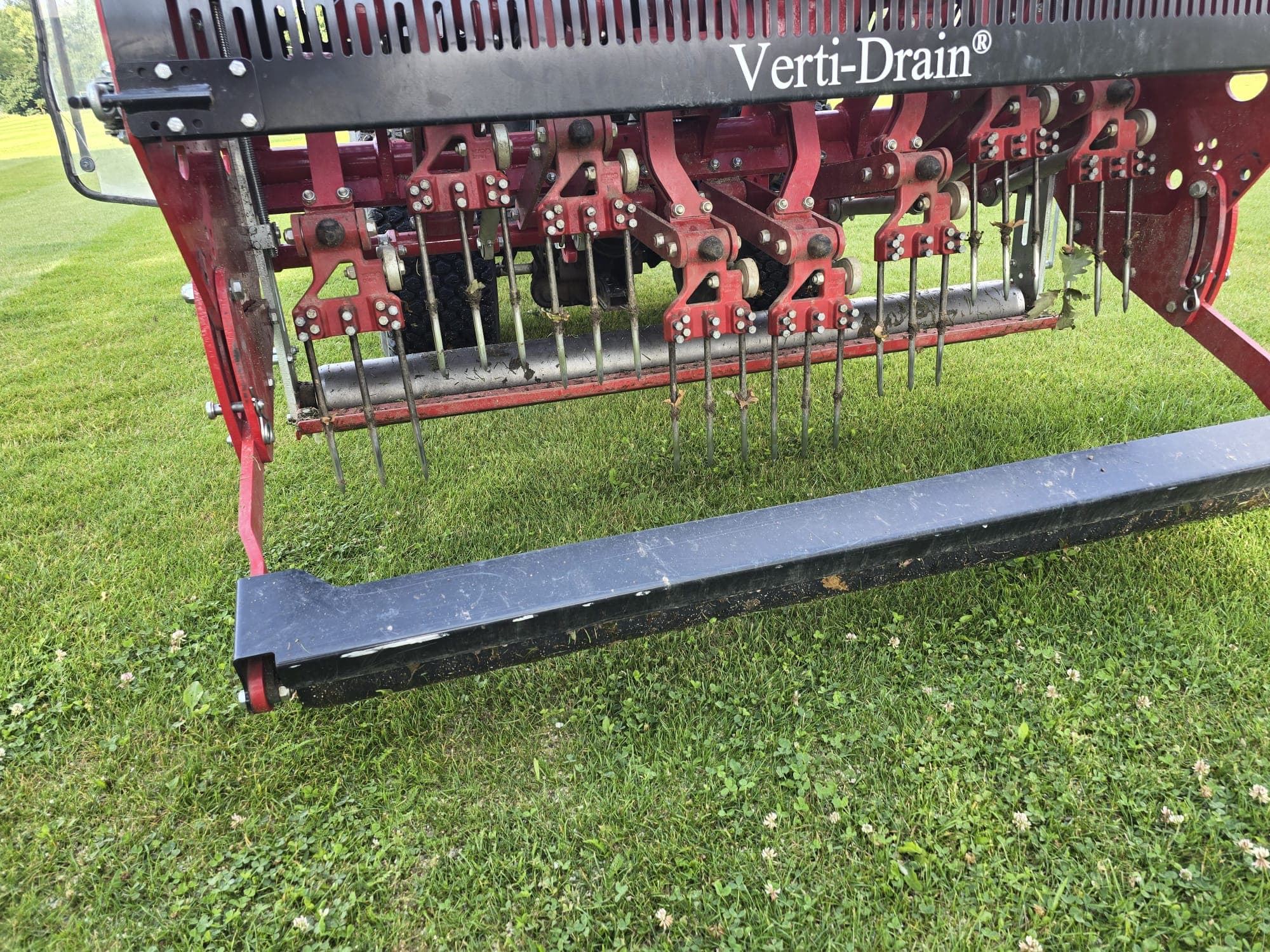 Detail hrotů provzdušňovacího stroje Verti-Drain nad trávníkem